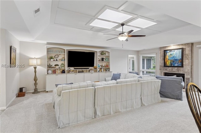 carpeted living room with a fireplace, built in features, and ceiling fan