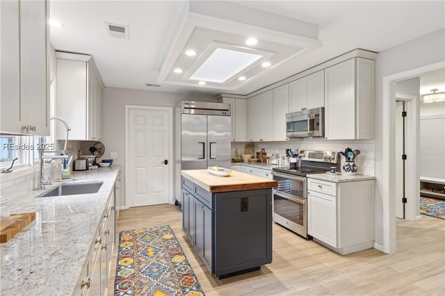 kitchen featuring wooden counters, stainless steel appliances, a center island, light hardwood / wood-style floors, and decorative backsplash