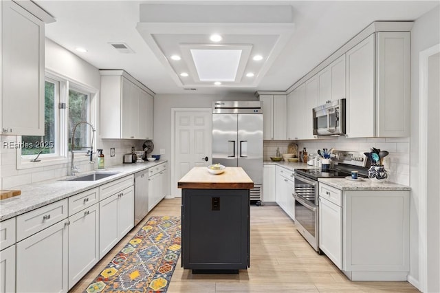 kitchen featuring stainless steel appliances, sink, wooden counters, and white cabinets