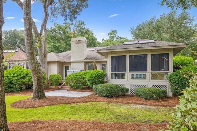 rear view of property with a sunroom and solar panels