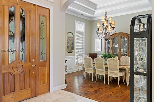 dining space with crown molding, a tray ceiling, a chandelier, and light hardwood / wood-style flooring