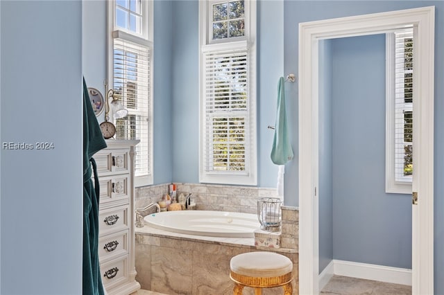 bathroom featuring tiled tub and a healthy amount of sunlight