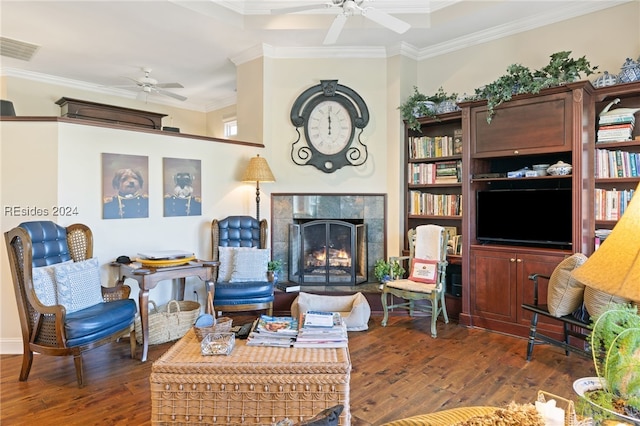 living room featuring a tile fireplace, dark wood-type flooring, ceiling fan, and crown molding