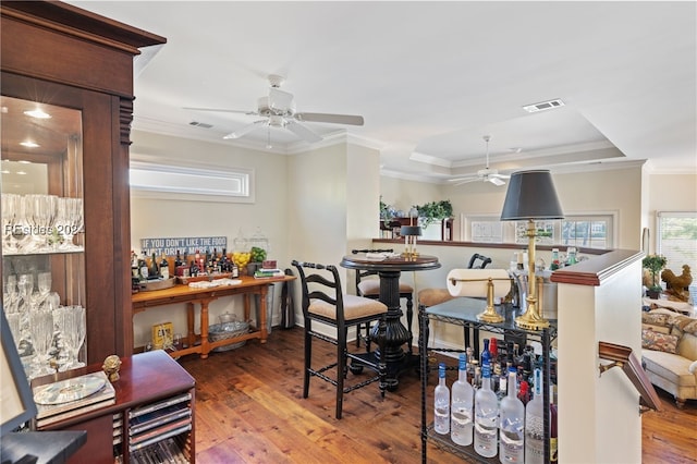 dining space with hardwood / wood-style floors, ornamental molding, a raised ceiling, and ceiling fan