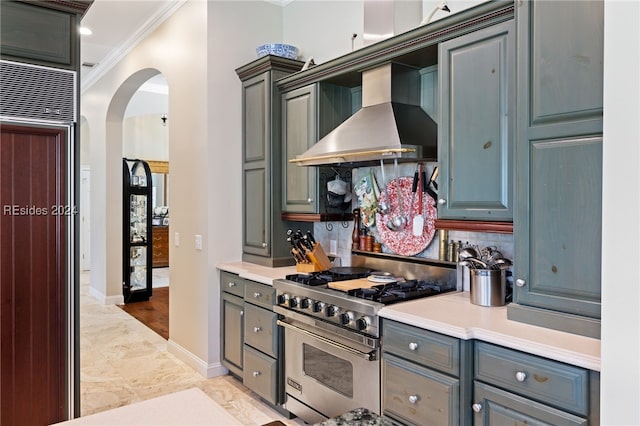 kitchen with wall chimney exhaust hood, gray cabinetry, ornamental molding, high quality appliances, and backsplash