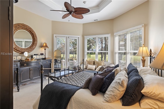 bedroom with ceiling fan, light colored carpet, and a raised ceiling