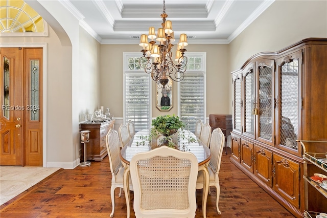 dining room featuring ornamental molding, dark wood-type flooring, an inviting chandelier, and a tray ceiling