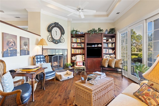 living room featuring crown molding, dark wood-type flooring, a tile fireplace, and ceiling fan