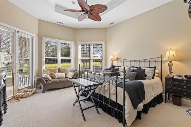 bedroom with light carpet, ceiling fan, and a tray ceiling