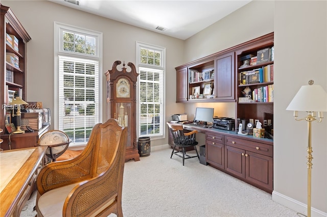 office space with light colored carpet, a healthy amount of sunlight, and built in desk