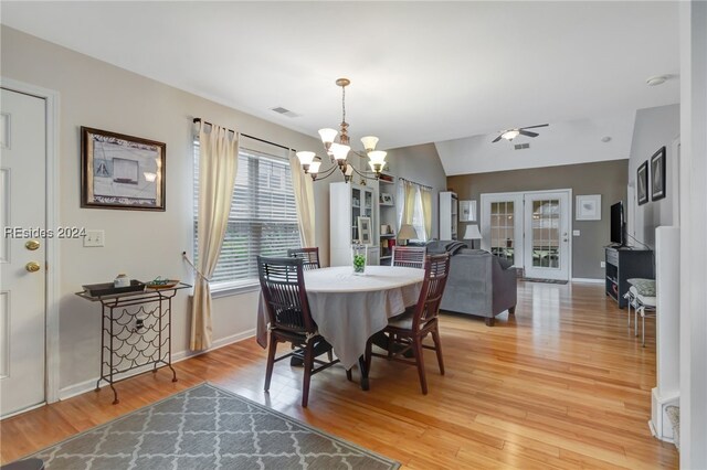 dining space featuring french doors, lofted ceiling, an inviting chandelier, and light hardwood / wood-style flooring