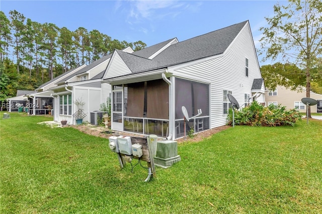 back of property featuring a lawn, a sunroom, and central air condition unit