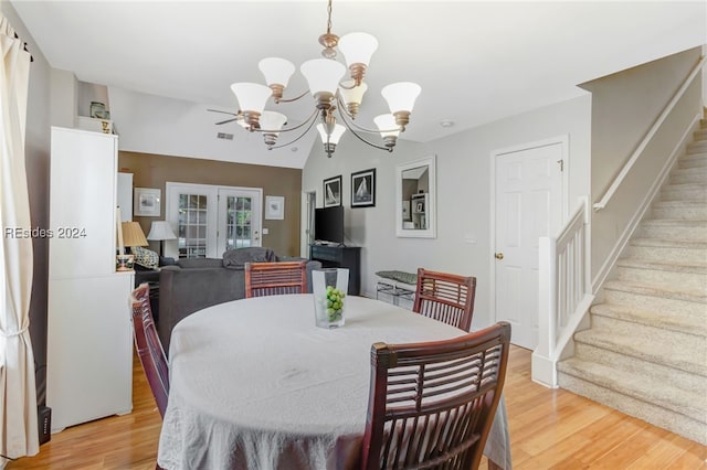 dining room featuring vaulted ceiling, an inviting chandelier, light hardwood / wood-style floors, and french doors