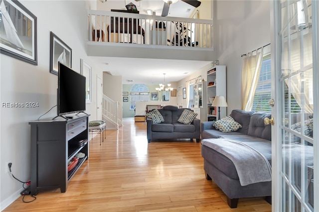 living room featuring a notable chandelier, a towering ceiling, a wealth of natural light, and wood-type flooring