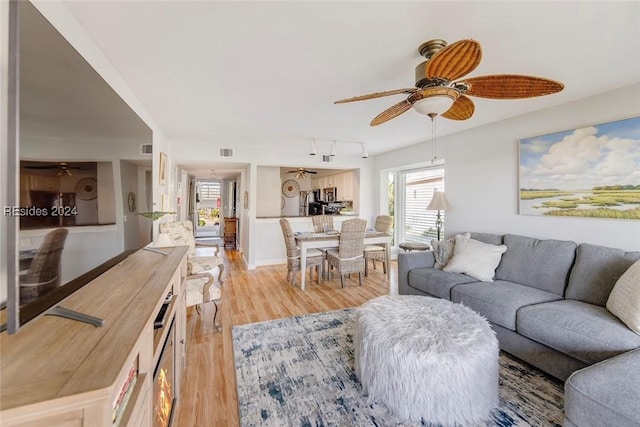 living room with track lighting, ceiling fan, and light wood-type flooring