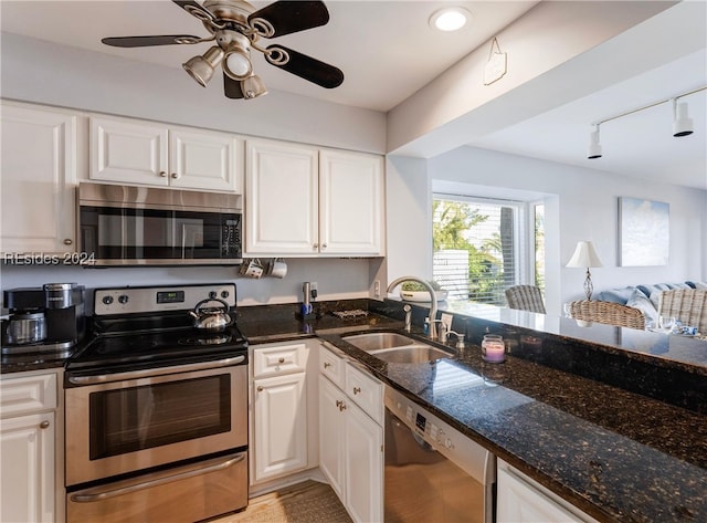 kitchen with appliances with stainless steel finishes, sink, track lighting, and white cabinets