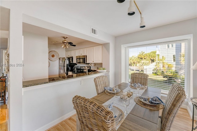 dining space with ceiling fan and light wood-type flooring