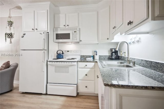 kitchen featuring white cabinetry, sink, dark stone countertops, white appliances, and light hardwood / wood-style flooring