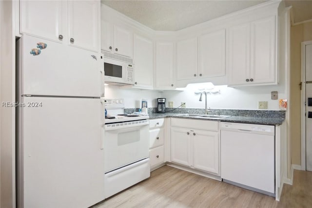 kitchen with white appliances, sink, light hardwood / wood-style flooring, and white cabinets