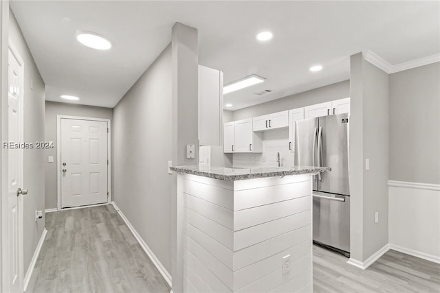 kitchen with white cabinetry, light hardwood / wood-style floors, light stone counters, and stainless steel refrigerator