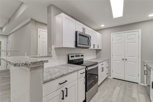 kitchen with appliances with stainless steel finishes, white cabinets, decorative backsplash, light stone counters, and kitchen peninsula