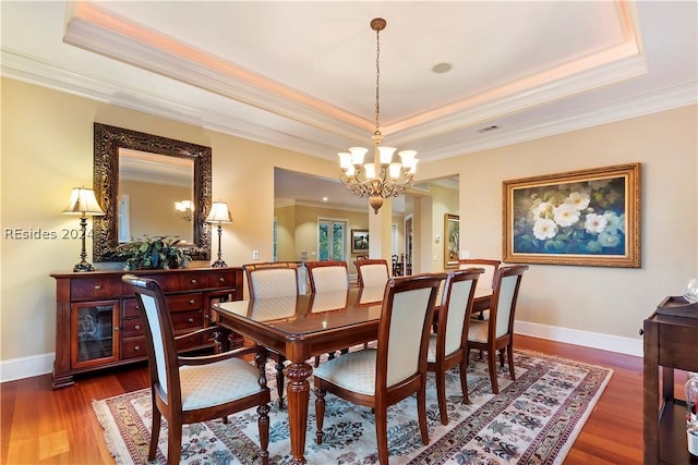 dining area featuring ornamental molding, dark hardwood / wood-style floors, a chandelier, and a tray ceiling