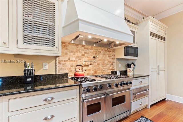 kitchen with range with two ovens, custom exhaust hood, black microwave, and white cabinetry