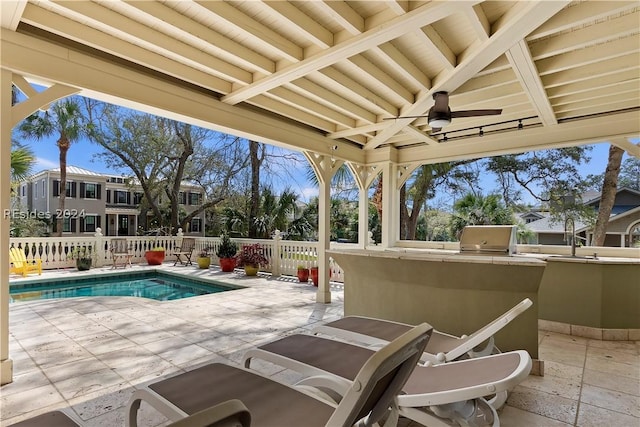 view of patio with a fenced in pool, ceiling fan, and exterior kitchen