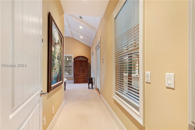 hallway with vaulted ceiling and light colored carpet