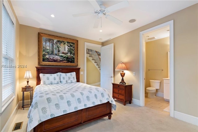 bedroom featuring ceiling fan, connected bathroom, and light colored carpet