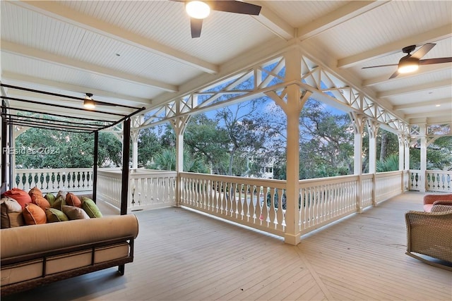 sunroom with ceiling fan and beam ceiling