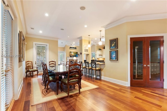 dining area featuring crown molding, light wood-type flooring, and french doors