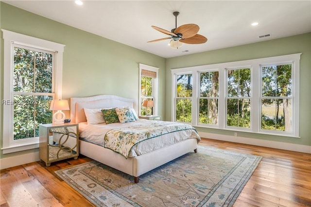 bedroom featuring multiple windows, hardwood / wood-style floors, and ceiling fan