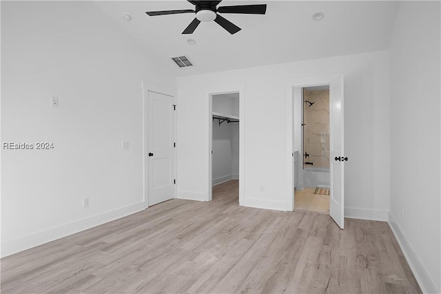 unfurnished bedroom with a walk in closet, ensuite bath, a closet, ceiling fan, and light hardwood / wood-style floors