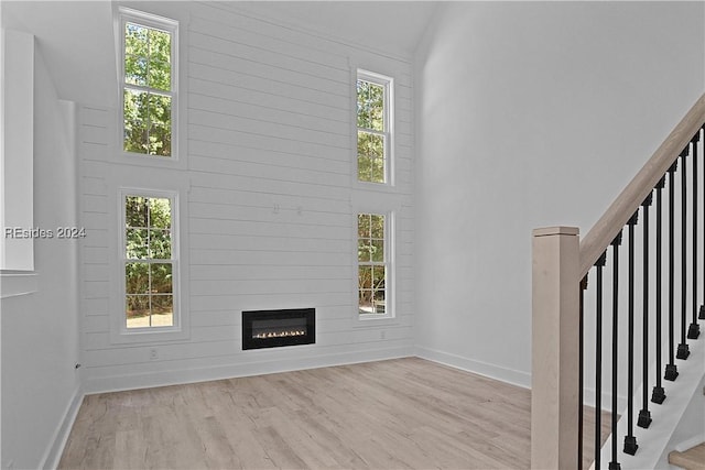 unfurnished living room with high vaulted ceiling, plenty of natural light, light hardwood / wood-style floors, and a large fireplace