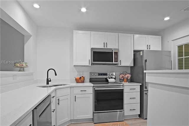 kitchen with stainless steel appliances, sink, and white cabinets