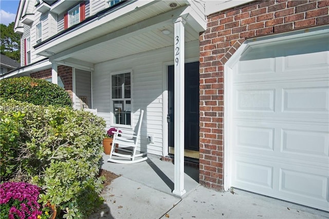 view of exterior entry with a garage and a porch