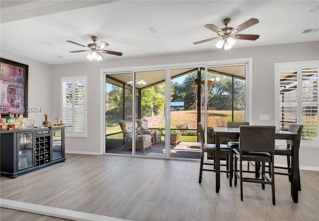 dining room featuring ceiling fan, indoor bar, light hardwood / wood-style floors, and wine cooler