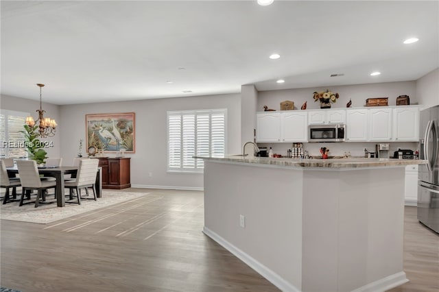 kitchen with pendant lighting, sink, appliances with stainless steel finishes, white cabinetry, and light wood-type flooring