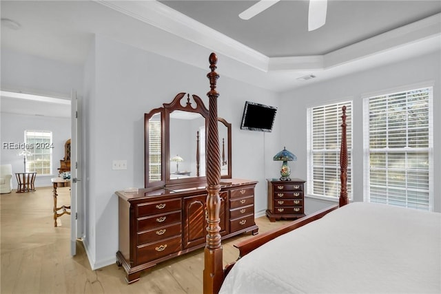 bedroom featuring light wood-type flooring, ceiling fan, and a tray ceiling