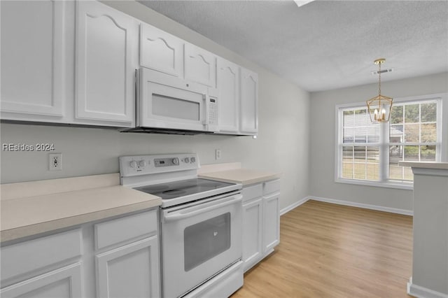 kitchen with white appliances, decorative light fixtures, and white cabinets