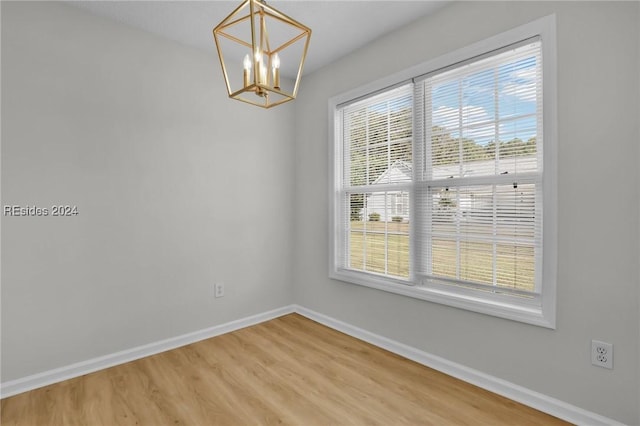 unfurnished room featuring hardwood / wood-style flooring and a notable chandelier