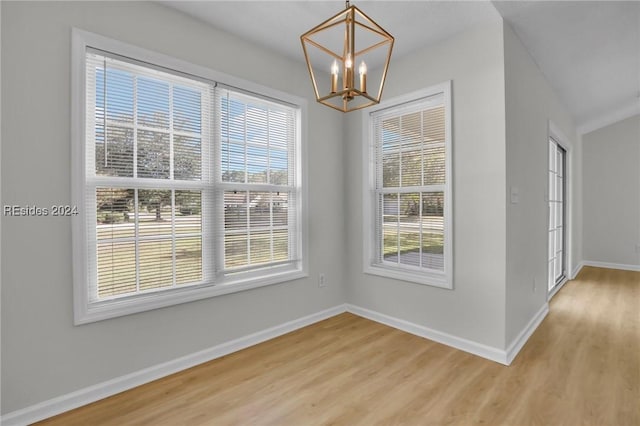 unfurnished dining area with an inviting chandelier and light hardwood / wood-style floors