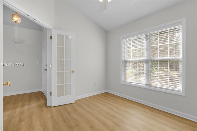 unfurnished room with ceiling fan, lofted ceiling, and light wood-type flooring