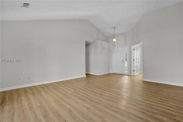 unfurnished room with high vaulted ceiling and light wood-type flooring