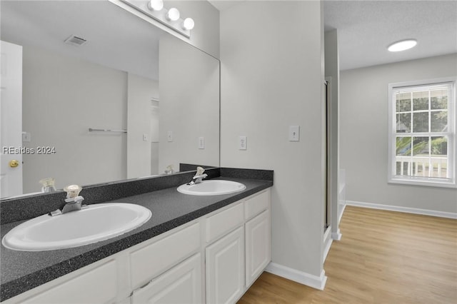 bathroom with vanity, hardwood / wood-style flooring, plus walk in shower, and a textured ceiling