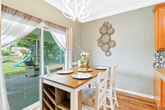 dining room with hardwood / wood-style flooring, crown molding, and a notable chandelier