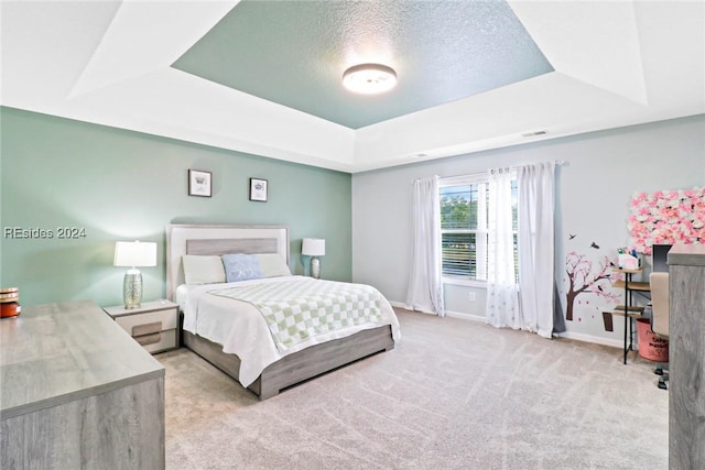 carpeted bedroom featuring a tray ceiling and a textured ceiling