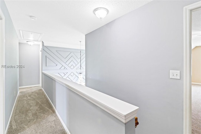 corridor with light carpet and a textured ceiling