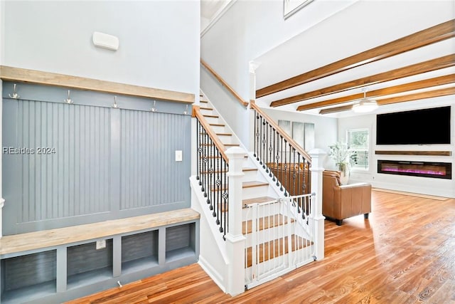 staircase with wood-type flooring and beam ceiling